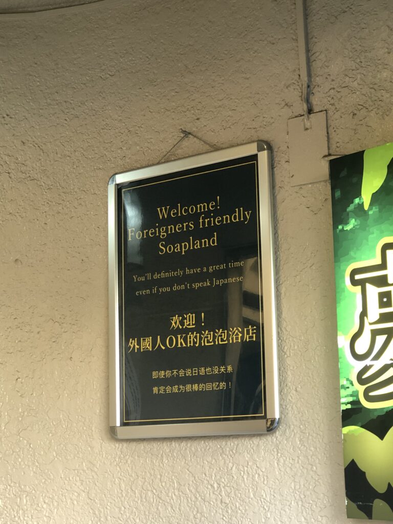 Sign welcoming foreigners in Japan, highlighting English and Chinese text at a tourist-friendly venue.