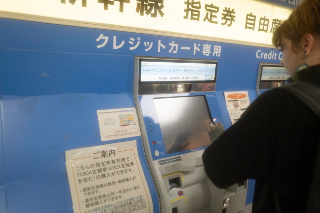 Tourist using a Japan rail pass ticket machine during Japan tour. Travel easily with rail passes.