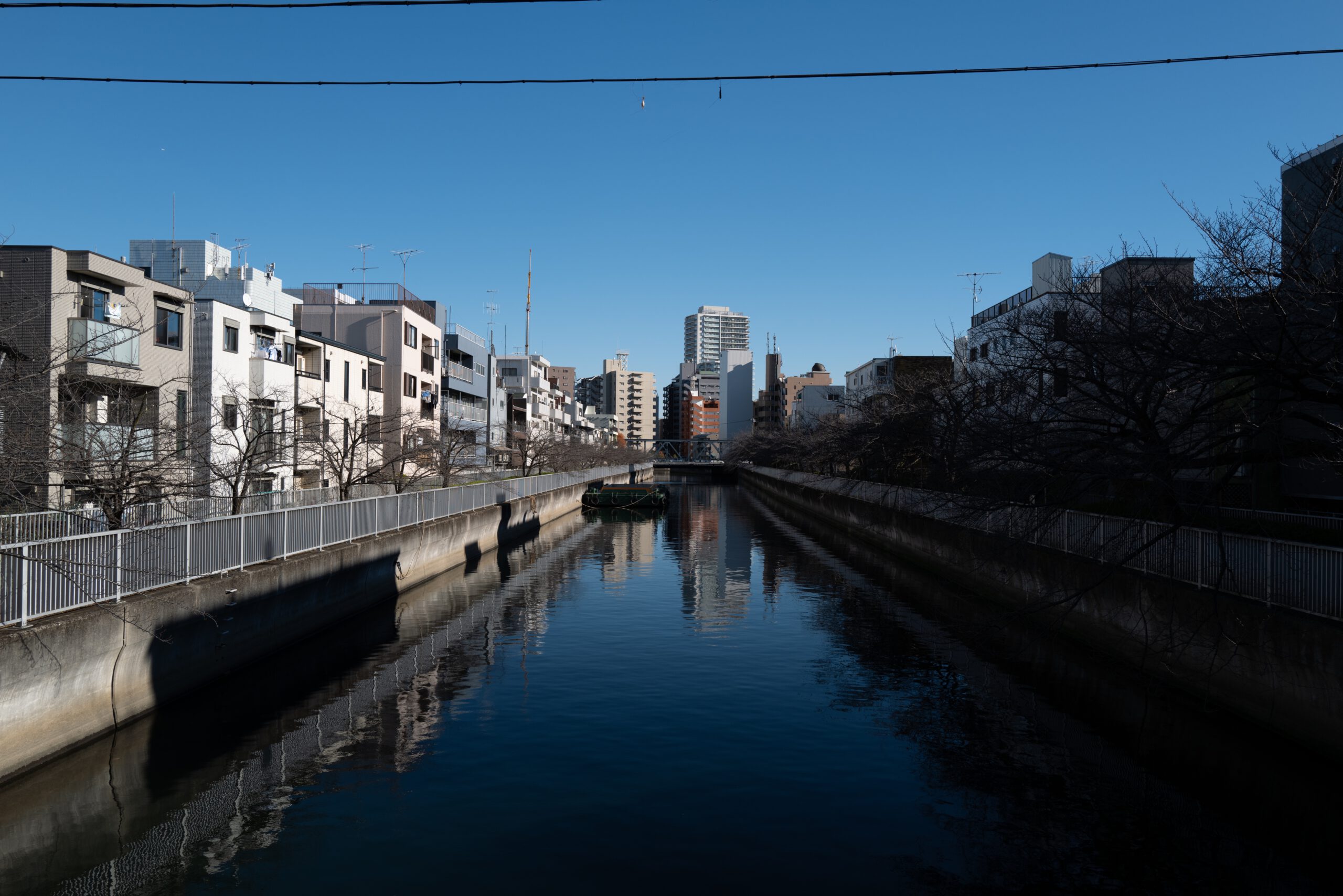 Urban canal view in Tokyo during a Japan tour, showcasing modern buildings and serene waters under a clear sky.