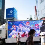 Colorful anime advertisement on a bustling Tokyo street, showcasing vibrant Japanese urban life.