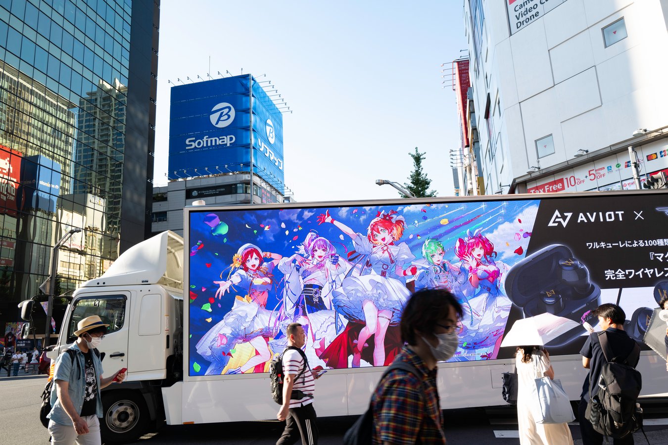Colorful anime advertisement on a bustling Tokyo street, showcasing vibrant Japanese urban life.