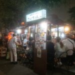 Night street food stall in Japan with people enjoying local dishes. Japan tour experience.