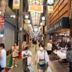 Busy Kyoto market street with tourists and locals exploring shops—an authentic Japan tour experience.