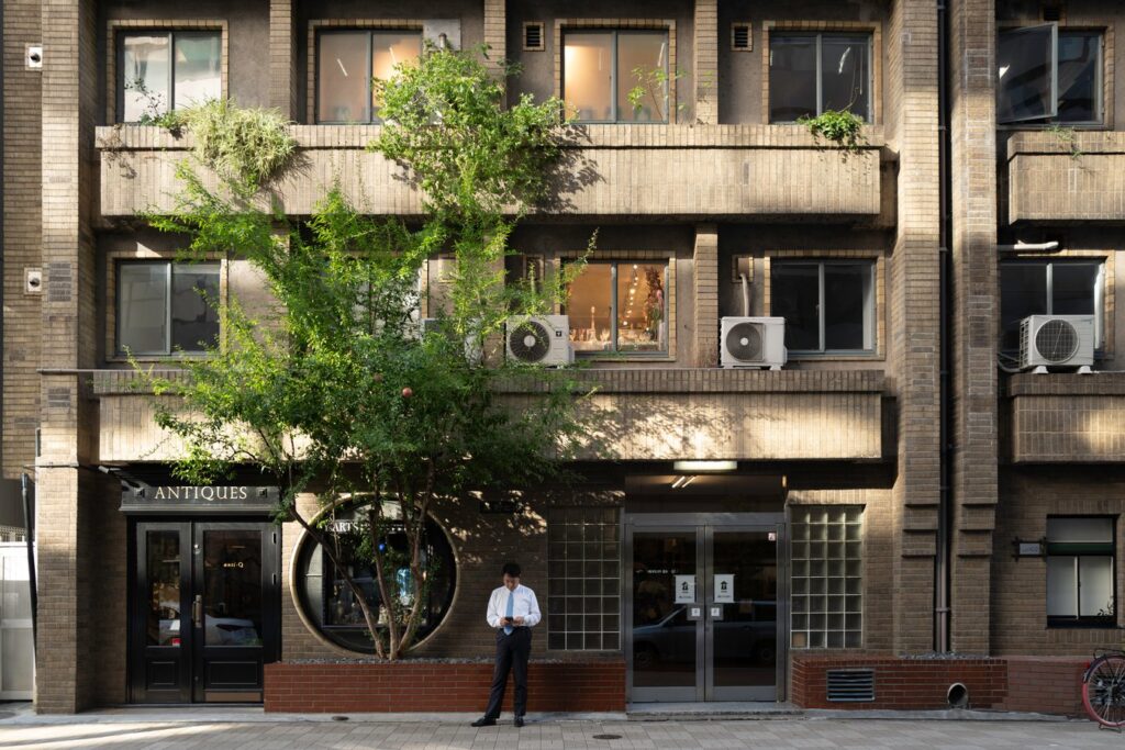 Urban street scene in Japan with a vintage building and a tree, suitable for cultural and historical tours.