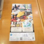 Colorful Saizeriya menu on wooden table, featuring Italian cuisine. Ideal dining spot for Japan tours.
