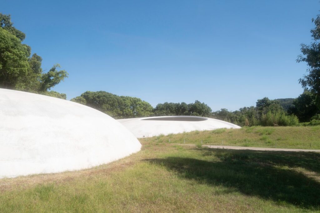 Modern architecture in Teshima Art Museum, Japan surrounded by greenery under a clear blue sky. Perfect for art tours.