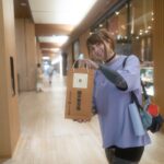 Touristes souriants tenant des sacs de souvenirs traditionnels tout en faisant des achats dans un centre commercial japonais avec un guide japonais.