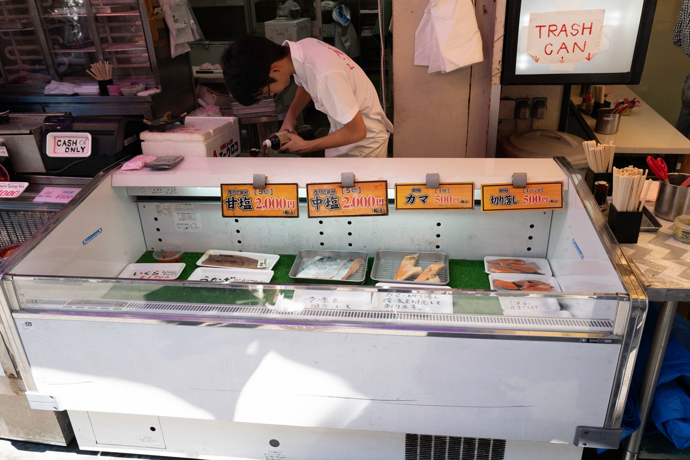 Street market in Japan selling fresh fish, man preparing food. Explore local cuisine on a Japan tour.