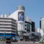 Shibuya crossing with bustling crowds and modern architecture on a sunny day, ideal for Japan city tours.