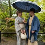 Couple in traditional kimonos with umbrella in Japanese garden. Perfect for cultural Japan tours.