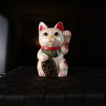 Lucky Maneki Neko cat beckoning prosperity on a Japan tour. Perfect for travel enthusiasts seeking cultural experiences.
