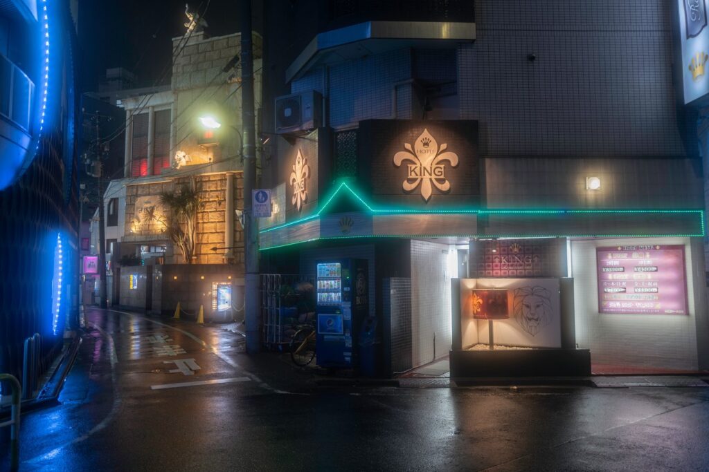 Moody night street view in Japan, featuring vibrant neon lights and urban architecture. Perfect for exploring Tokyo nightlife.