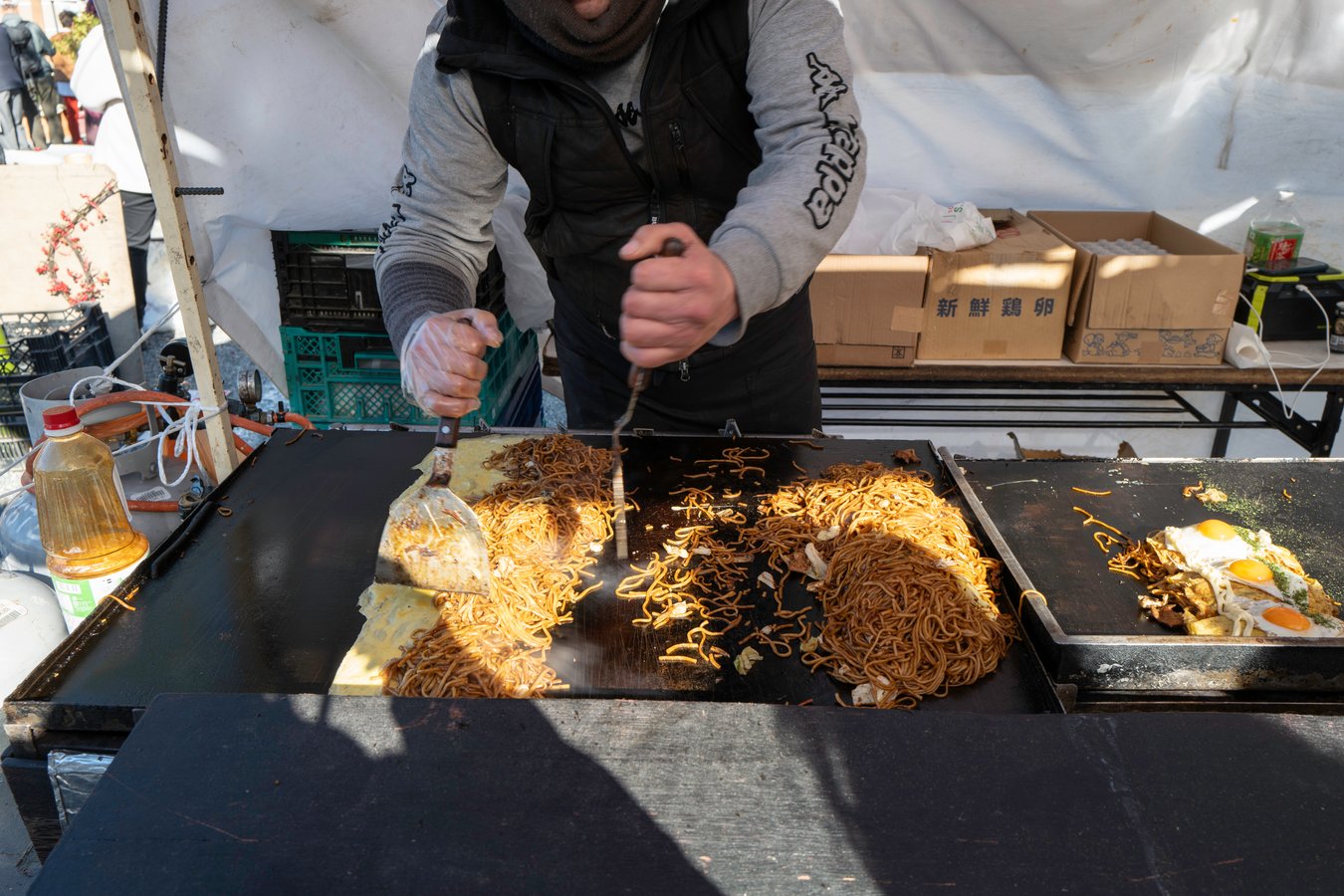 Street vendor cooking yakisoba at a Japanese market, showcasing local cuisine on a Japan tour adventure.
