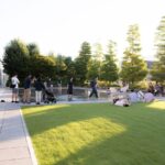 Visitors enjoying a sunny day in a modern Japanese park, perfect for relaxation during Japan tours.